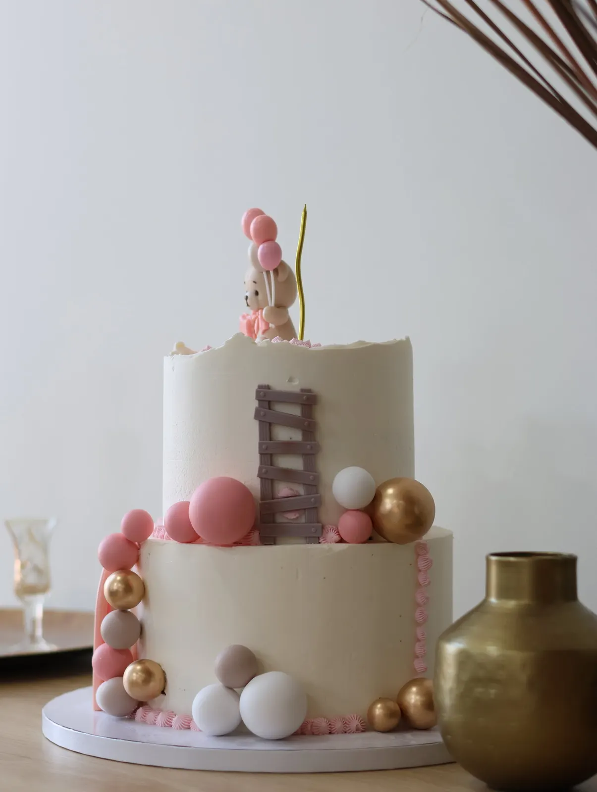 Bolo rosa de dois andares com urso e vaso dourado